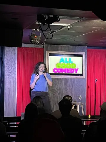 A comedian in a blue top addressing the audience