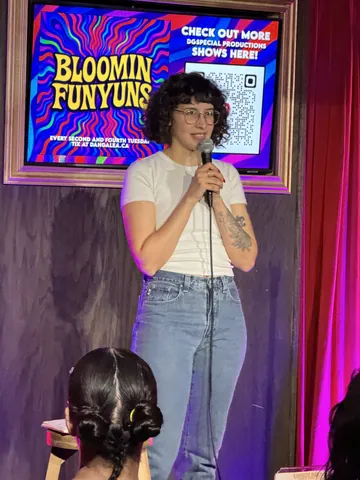 A comedian in a white T-shirt performing with the audience in the foreground