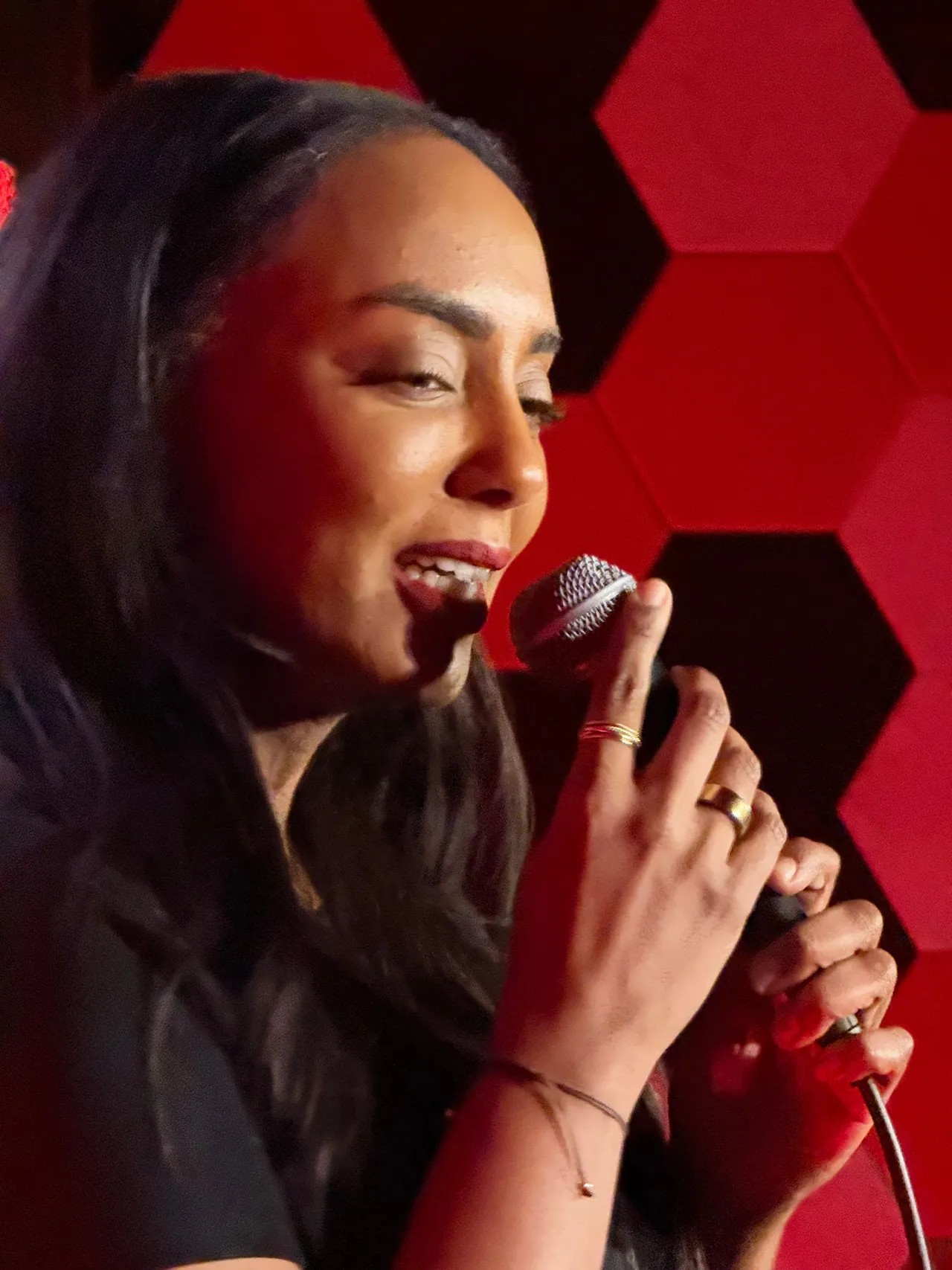 A close view of a performer holding a microphone beneath red stage lights