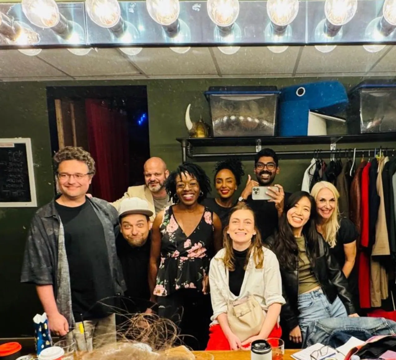Friends gathered under dressing-room mirror lights