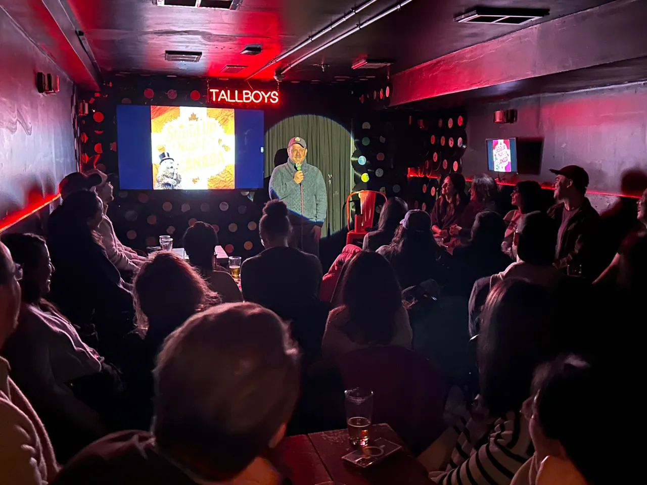 A comedian performing for a packed audience at Tallboys